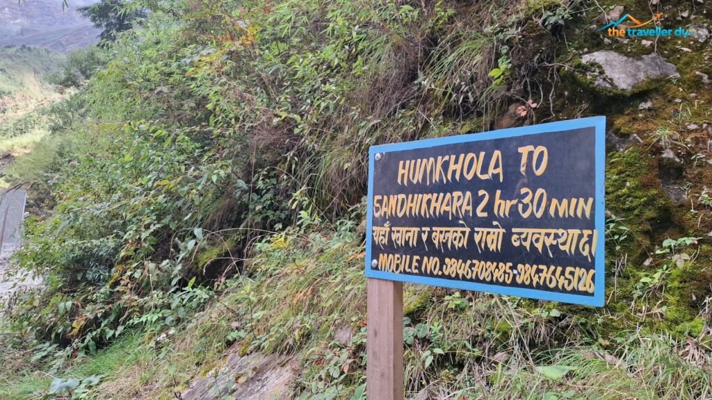 Signboard reading Humkhola to Sandhikharka 2 hr 30 min with homestay phone numbers